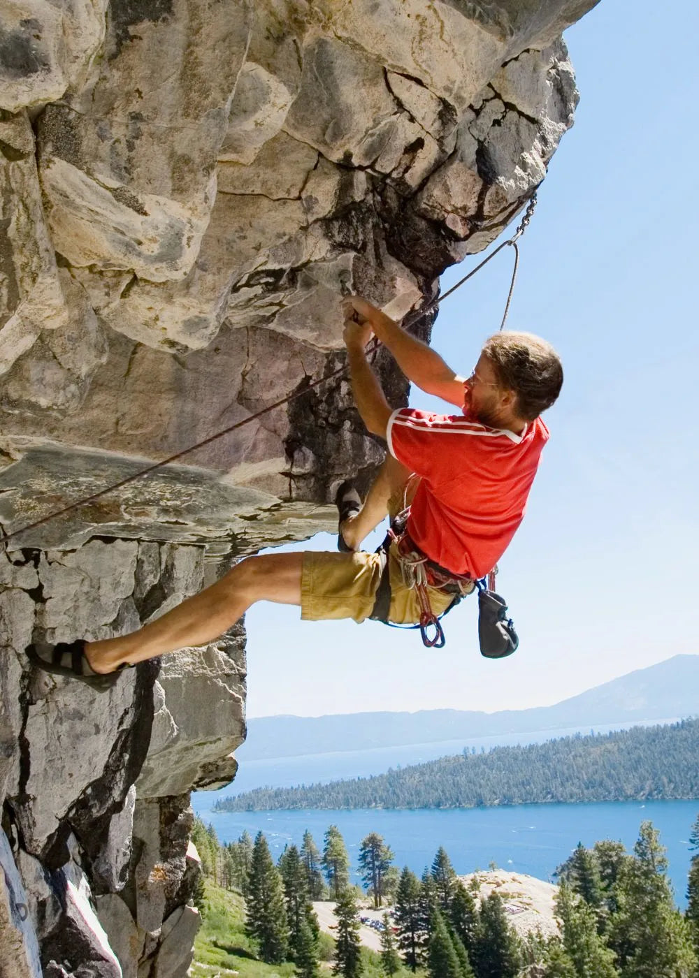 A climber in a red shirt and yellow shorts uses Handexer grip strength for rock climbing, highlighting the importance of grip strength measurement tools like a Hand Dynamometer Grip Strength Meter for isometric handgrip exercises.