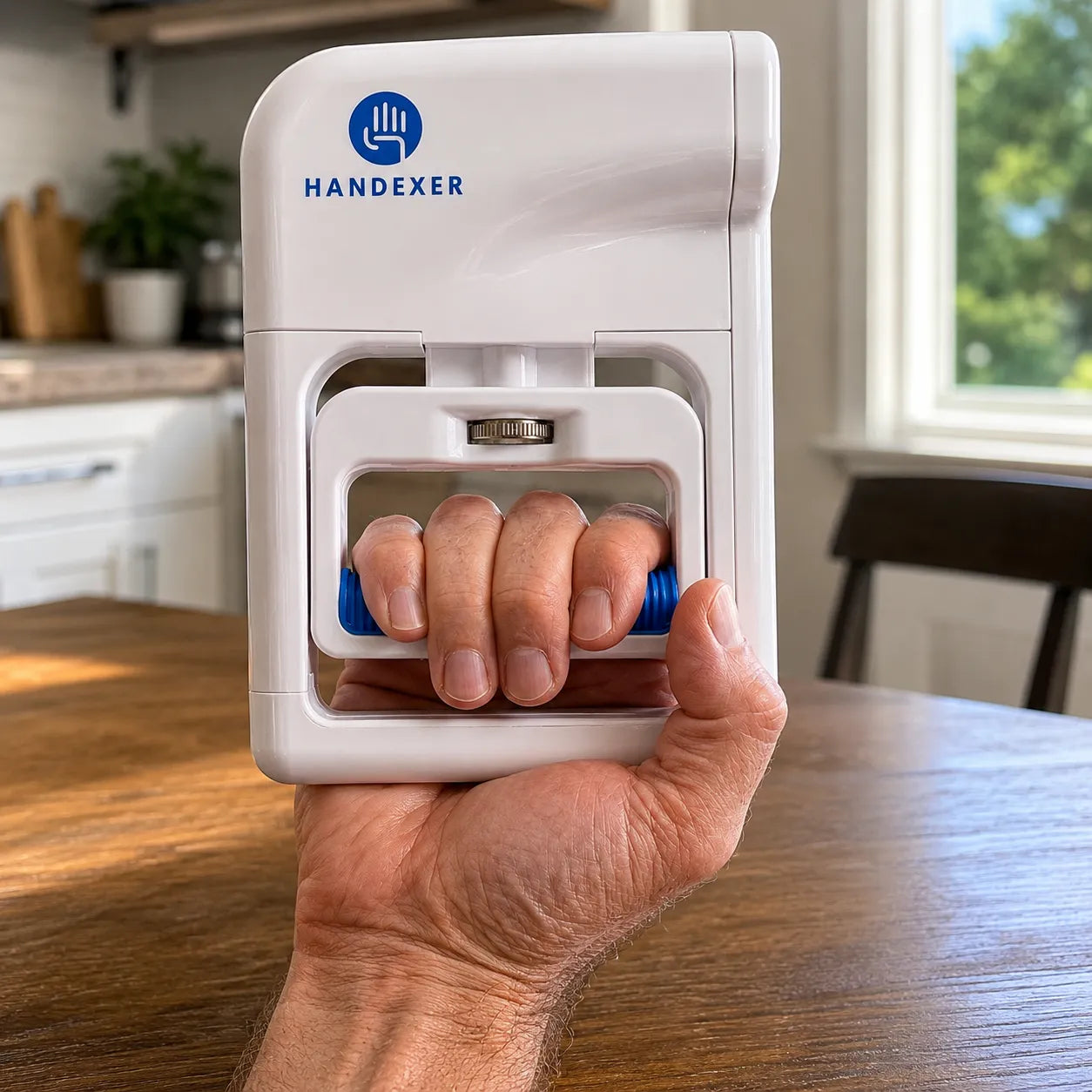 Close-up of an older hand using a Handexer digital hand dynamometer at a wooden kitchen table