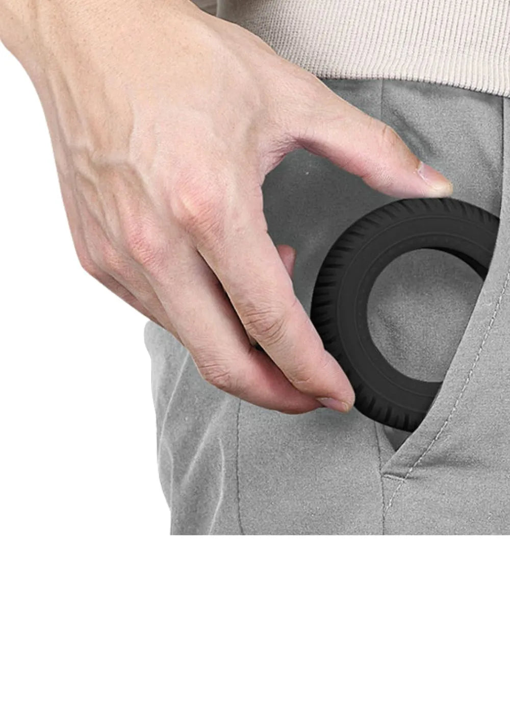 A hand holding a black Handexer grip strength hand dynamometer, which is being placed into the pocket of gray pants. The dynamometer is a tool for grip strength measurement and is suitable for isometric grip exercises.