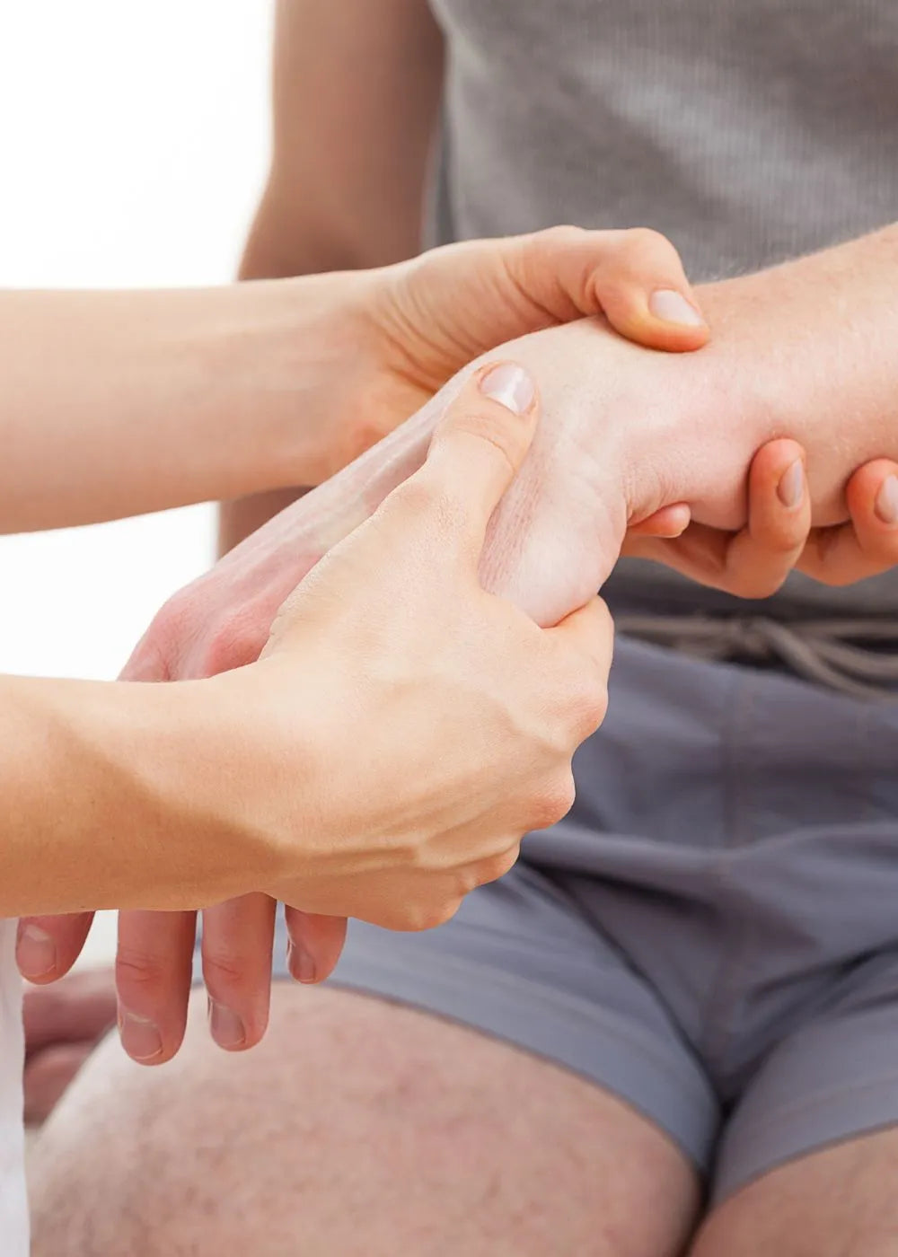 Two hands are examining or assessing a wrist, which is relevant to grip strength measurement as it involves hand and wrist interaction. Keywords: grip strength measurement, hand, wrist, Handexer.